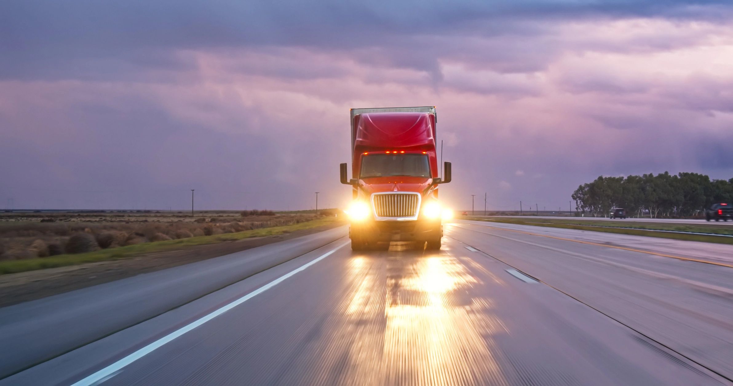 Cargo truck driving on highway at sunset